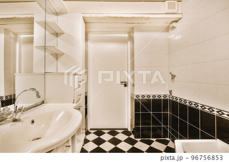 Sinks with mirrors and clean bathtub located near shower box with glass door in modern bathroom with white tiled walls 96756853