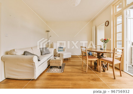 Shabby wooden table with chairs and vase located near comfortable couch against light walls with decorations and TV in modern apartment Shabby wooden table with chairs and vase located near comfortable couch against light walls with decorations and TV in modern apartment 96756932