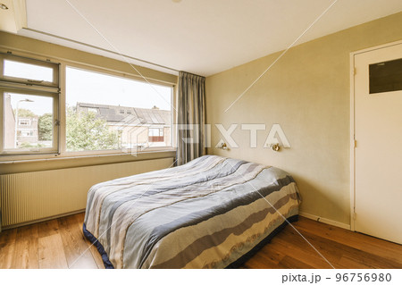 Minimalist interior design of small bedroom with soft bed placed in corner and wooden wardrobe and shelves with lamp illumination Minimalist interior design of small bedroom with soft bed placed in corner and wooden wardrobe and shelves with lamp illumination 96756980