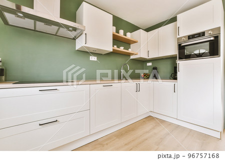 Fragment of interior of light narrow home kitchen with minimalist style white furniture with sink and stove 96757168