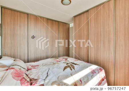 Home interior design of bedroom with bed and wooden wardrobe placed in corner near window in modern apartment Home interior design of bedroom with bed and wooden wardrobe placed in corner near window in modern apartment 96757247