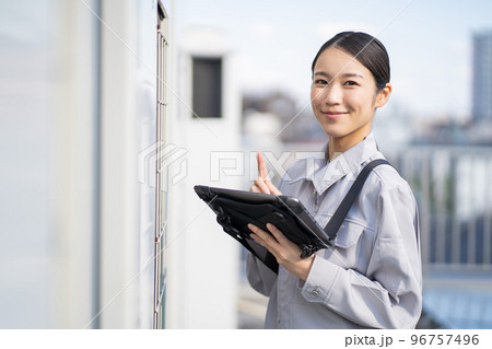 エアコンの室外機を点検する若い女性の作業員 エアコンの室外機を点検する若い女性の作業員 96757496