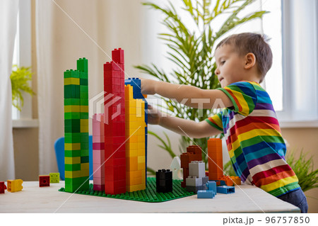 Overjoyed baby boy successful assembling multicolored plastic blocks tower constructing Overjoyed baby boy successful assembling multicolored plastic blocks tower constructing 96757850