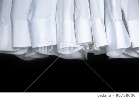 Male business wardrobe many clean white shirt sleeve hanging isolated on black background 96758006