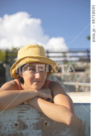 Smiling tanned female in yellow hat relaxing posing on sunny beach enjoy summer travel vacation Smiling tanned female in yellow hat relaxing posing on sunny beach enjoy summer travel vacation 96758095