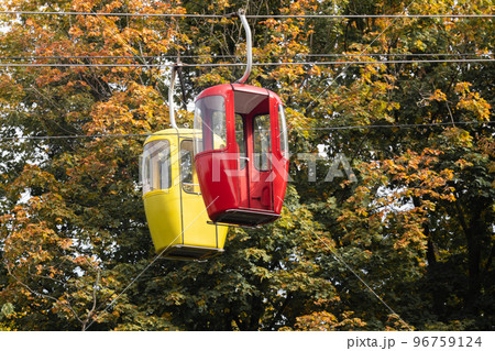 Red and yellow cable car cabins in autumn forest 96759124