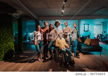 Businesswoman in a wheelchair on break in a modern office with her team in the background 96759863