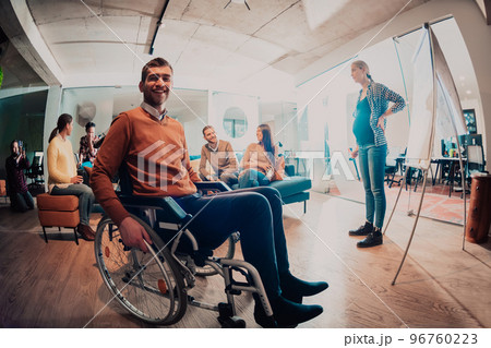 A pregnant businesswoman leads a creative meeting of a diverse business team in a modern coworking A pregnant businesswoman leads a creative meeting of a diverse business team in a modern coworking 96760223