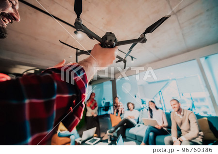 A bearded man in a modern office explaining to his young diverse team how a drone working A bearded man in a modern office explaining to his young diverse team how a drone working 96760386