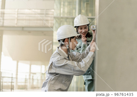 女性の先輩エンジニアに教わりながら作業する男性後輩エンジニア 96761435