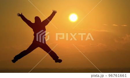 両手両足を広げてジャンプする女性シルエット_夕日背景ワイド 両手両足を広げてジャンプする女性シルエット_夕日背景ワイド 96761661
