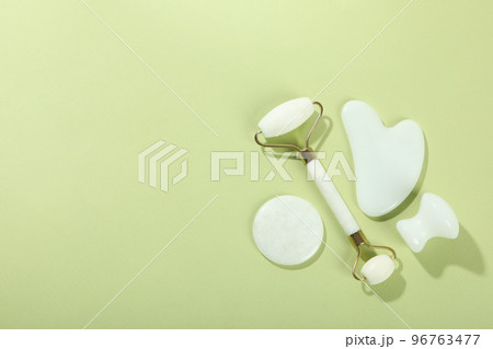 Lifting and toning treatment concept with gua sha on green background 96763477