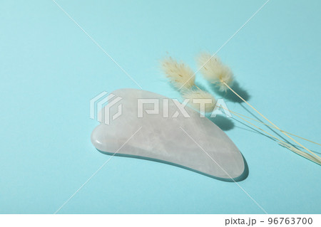 Lifting and toning treatment concept with gua sha on blue background Lifting and toning treatment concept with gua sha on blue background 96763700