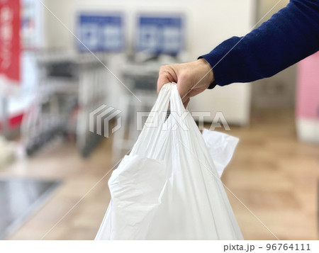 スーパーでレジ袋を持つ手元 96764111