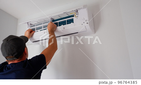 Maintenance of the air conditioner. A technician is cleaning the filter. View of the hands from the back. Maintenance of the air conditioner. A technician is cleaning the filter. View of the hands from the back. 96764385