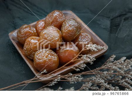Three flavored preserved chinese plums (Preserved fruits) on wooden plate. Its flavour has sour, salty and sweet taste. Three flavored preserved chinese plums (Preserved fruits) on wooden plate. Its flavour has sour, salty and sweet taste. 96765866