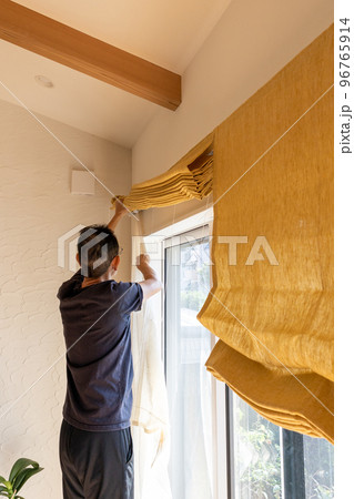 家のシェードを洗濯しようと取り外しているシニア男性 家のシェードを洗濯しようと取り外しているシニア男性 96765914