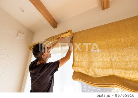 家のシェードを洗濯しようと取り外しているシニア男性 家のシェードを洗濯しようと取り外しているシニア男性 96765916