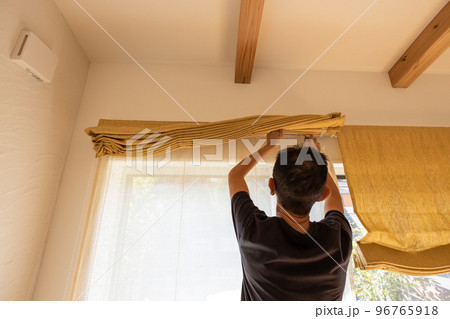 家のシェードを洗濯しようと取り外しているシニア男性 家のシェードを洗濯しようと取り外しているシニア男性 96765918
