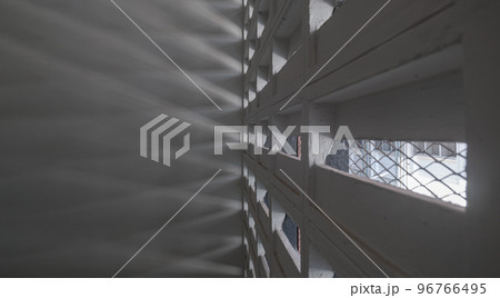 The sunlight shines through light channels wall of old gymnasium. Concrete walls have holes for sunlight to penetrate through the holes from the outside. 96766495