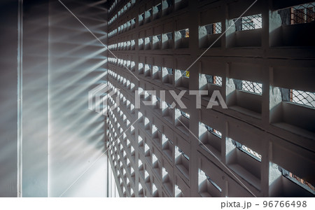 The sunlight shines through light channels wall of old gymnasium. Concrete walls have holes for sunlight to penetrate through the holes from the outside. 96766498