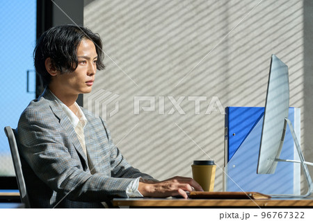 オフィスの窓辺で仕事をする若いビジネスマン オフィスの窓辺で仕事をする若いビジネスマン 96767322