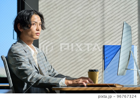 オフィスの窓辺で仕事をする若いビジネスマン オフィスの窓辺で仕事をする若いビジネスマン 96767324