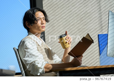 オフィスの窓辺で仕事をする若いビジネスマン オフィスの窓辺で仕事をする若いビジネスマン 96767419