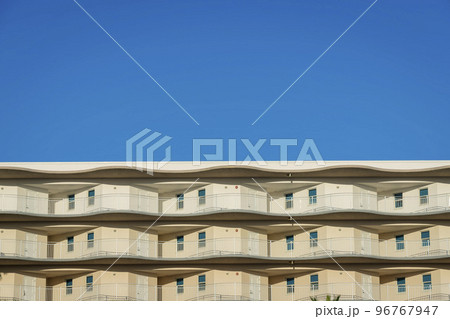 View of a building from below with painted beige walls and white doors at balconies in Destin, FL View of a building from below with painted beige walls and white doors at balconies in Destin, FL 96767947