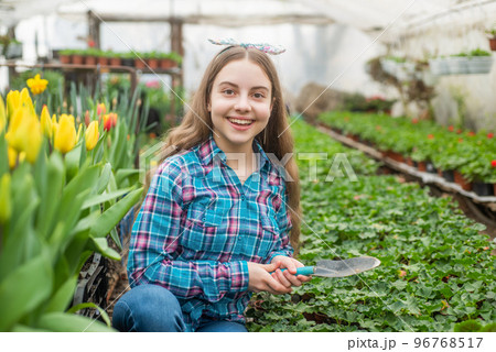 happy teen girl florist planting pot plants in greenhouse, spring 96768517