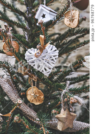 Christmas tree decorated with heart-shaped wicker wreath and other handmade Christmas zero-waste ornaments. Zero-waste Christmas decoration 96768779