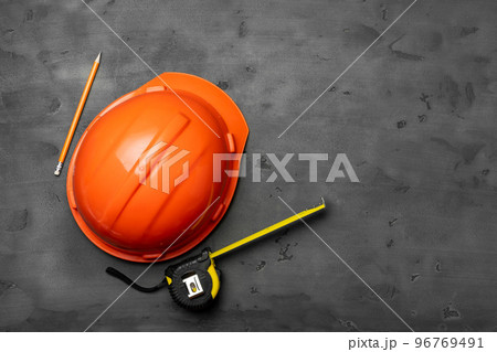 Orange hardhat, ruler and pencil on black background 96769491