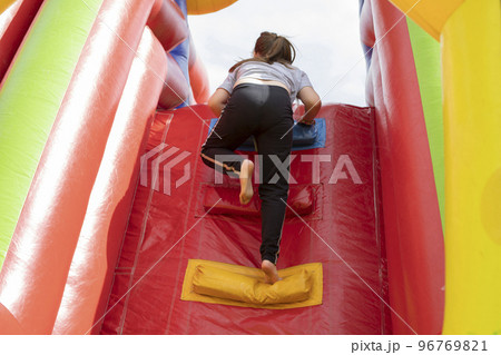 Child on slide. Inflatable slide for children. Baby climbs up. Play area in summer. Child on slide. Inflatable slide for children. Baby climbs up. Play area in summer. 96769821