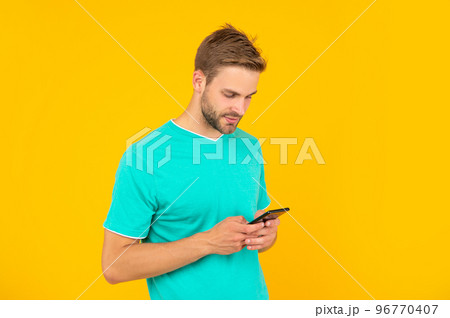 guy with bristle chatting on smartphone on yellow background, technology 96770407