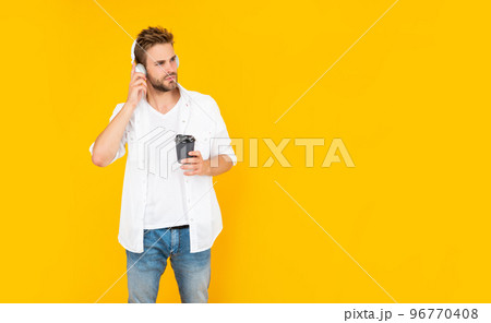 unshaven young man in headphones drinking coffee on yellow background with copy space, lifestyle unshaven young man in headphones drinking coffee on yellow background with copy space, lifestyle 96770408