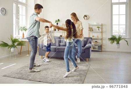 Happy family mom, dad, daughter and son playing leading a round dance at home in living room. Happy family mom, dad, daughter and son playing leading a round dance at home in living room. 96771848