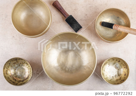 Tibetan singing bowls with sticks used during mantra meditations on beige stone background, top view, flat lay 96772292