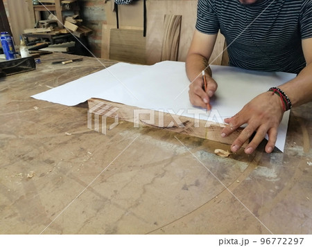An Anonymous Carpenter Working on New Project at his Workshop. Table top view of unrecognizable man drawing n An Anonymous Carpenter Working on New Project at his Workshop. Table top view of unrecognizable man drawing n 96772297