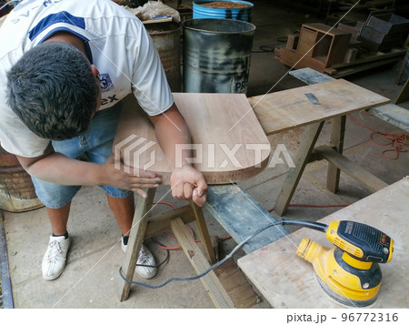 man using woodworking sander. sander in hand, adult man sanding a piece of furniture 96772316