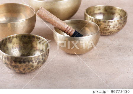 Tibetan singing bowls with sticks used during mantra meditations on beige stone background, copy space. 96772450