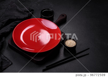 Empty plate with wooden sticks for Asian food on a dark concrete background 96772509