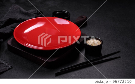 Empty plate with wooden sticks for Asian food on a dark concrete background 96772510