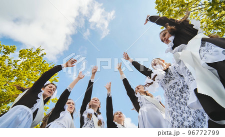 Happy Russian school graduates are stretching their hands on their last school day. 96772799