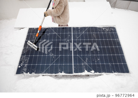 Woman cleans solar panels from snow 96772964