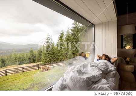 Woman lying on window sill with great view on mountains Woman lying on window sill with great view on mountains 96773030
