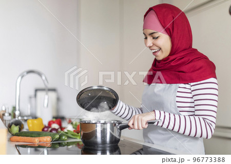 Middle eastern wife wearing hijab cooking at home, copy space Middle eastern wife wearing hijab cooking at home, copy space 96773388