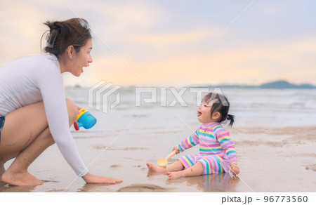 Happy asian mother and daughter playing sand and build sand castle at beach, Happy family activity concept. 96773560