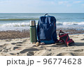 A thermos of tea and a backpack against the backdrop of nature. Walking along the seashore. 96774628