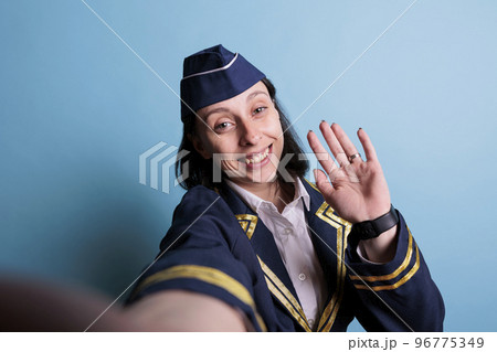 Smiling stewardess taking selfie first person view, airplane flight attendant making photo on smartphone front camera, fpv. Young attractive air hostess in air worker uniform portrait Smiling stewardess taking selfie first person view, airplane flight attendant making photo on smartphone front camera, fpv. Young attractive air hostess in air worker uniform portrait 96775349