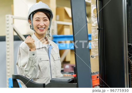 フォークリフトを乗ってガッツポーズをする女性作業員 フォークリフトを乗ってガッツポーズをする女性作業員 96775930